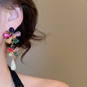Close-up of gold-plated flower earrings with colorful crystals and pearl drop detail