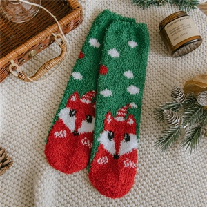 Close-up of cozy Christmas coral fleece socks with fox patterns on a white knit surface