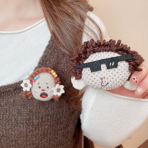 Detailed view of handmade plush cartoon brooches showing yarn texture and felt material
