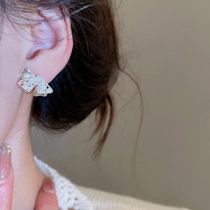 Close-up of elegant bow stud earrings with zircon stones worn by a model