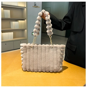 Detail of beige plush tote with striped faux fur texture and gold chain pompom handle