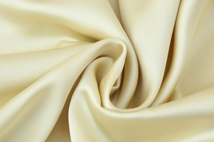 Macro shot of champagne gold satin fabric with elegant drapes and silk texture