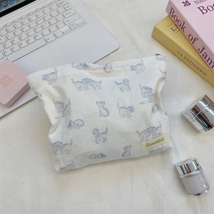 Flat lay of cat print makeup bag with skincare products on a minimalist workspace