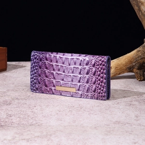 Detail of purple crocodile-patterned long wallet with a golden metal centerpiece logo