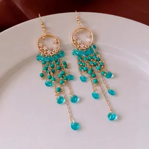 Ethnic style circle earrings with turquoise beads and crystal tassels on white ceramic plate