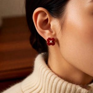 Close-up of a red clover stud earring worn by a model in a warm vintage setting