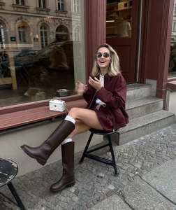 Outdoor shot of a woman in a burgundy vintage jacket and matching shorts with brown boots