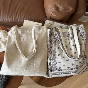 Minimalist cotton linen tote bag and paisley print shoulder bag on a leather sofa