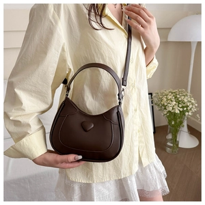 Deep brown half-moon saddle bag with heart detail and adjustable strap for women