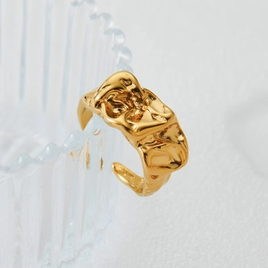 Irregular fluid gold open ring with lava texture hanging on a glass rim for women