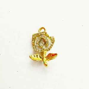 Macro view of rose-shaped pendant with gold finish, white enamel, and crystal inlay