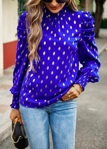 Detail of blue high neck blouse featuring gold foil print and elegant puff sleeves