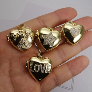 Golden heart locket pendants with star and LOVE engravings held in hand