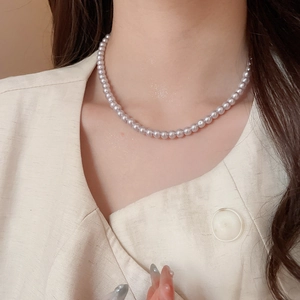 Detailed close-up of a classic single-strand pearl necklace worn on a female model neck