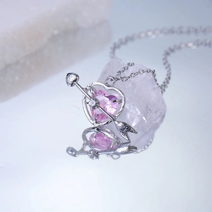 Macro shot of pink heart zircon necklace with silver Cupid arrow pendant and mirror reflection