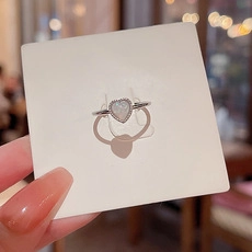 Detail of a silver heart ring with a white opal stone on a clean white card display