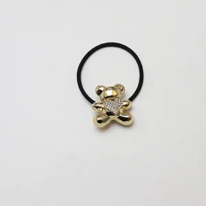 Detail of golden metal bear hair tie with sparkling rhinestone heart on black elastic