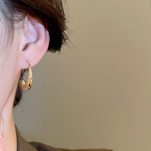 Close-up of a 14k gold plated geometric teardrop earring worn on a model's ear