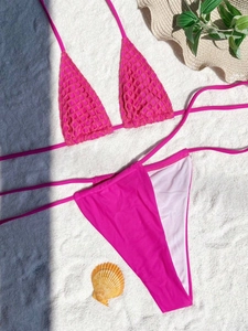 Detail of rose red mesh bikini top and high cut bottoms on a white sand beach