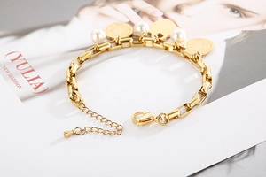 Détail du bracelet chaîne dorée avec perles blanches, médailles et pendentif cœur