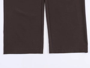 Gros plan des ourlets de pantalon marron chocolat montrant les coutures et la texture du tissu