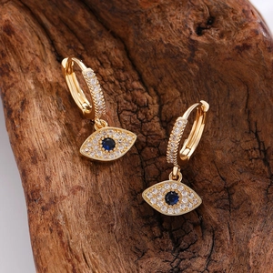 Detail of gold evil eye hoop earrings with blue stones and crystals on wood
