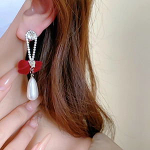 Close-up of velvet bow earrings with dangling pearls and crystal teardrop accents