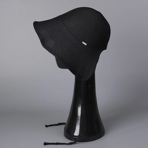 Detail of black knit bucket hat with silver metal logo tag and woven chin straps