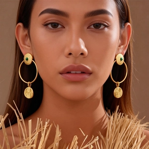24K gold plated textured hoop earrings with green gemstone on model in warm studio lighting