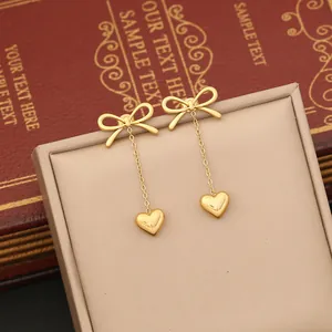 Macro detail of elegant golden bow and heart pendant drop earring with pearl tassel