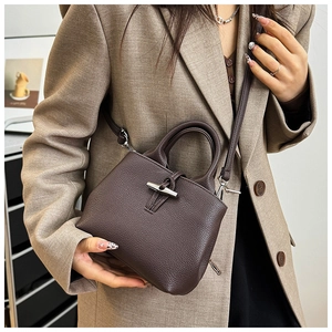 Detail of silver bamboo toggle closure on a dark brown textured leather bucket bag