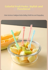 Colorful cartoon animal fruit forks in a glass bowl with fresh kiwi and melon slices