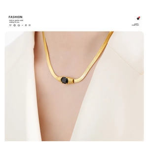 Detail of gold snake chain necklace featuring a black oval gemstone on a female model