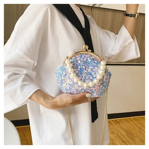 Detail of mini sequin shell bag with large pearl handle and elegant gold chain strap