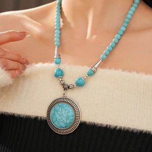 Detail of bohemian turquoise beaded necklace with large round engraved pendant