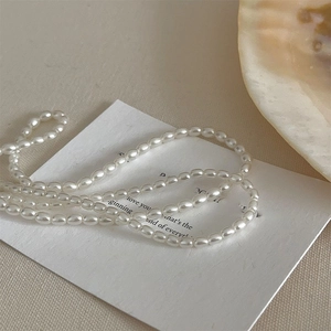 Detailed close-up of elegant cream white pearl choker necklace on a poetic card