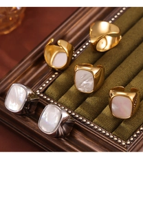 Macro view of gold and silver plated wide band rings with inlaid white mother of pearl