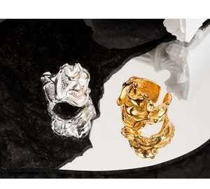 Close-up of irregular pleated gold and silver S925 rings on a reflective mirror surface