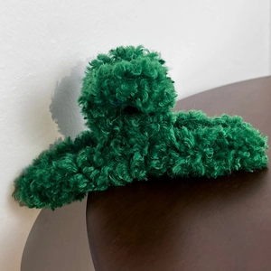 Detailed view of dark green plush faux fur hair claw clip on a wooden surface