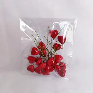 Macro detail of red heart-shaped foam craft picks with green wire stems in packaging