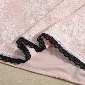 Detalle de tela rosa con encaje floral blanco y ribete de encaje de pestañas negro