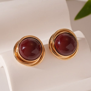 Détail de boucles d'oreilles spirale dorées avec perles rouges de style vintage