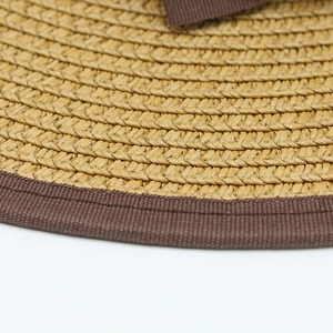 Close-up of straw sun hat featuring detailed weave texture and brown ribbon edging