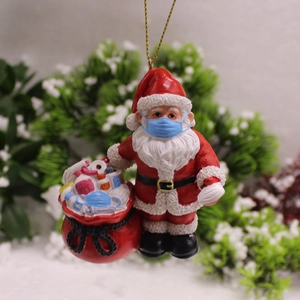Père Noël en résine avec masque médical tenant un sac de cadeaux rempli d'articles sanitaires