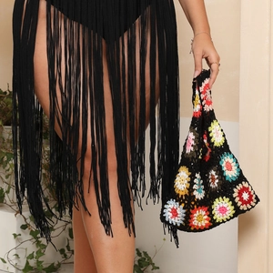 Detail of crochet tote bag with colorful flower patterns and black fringe skirt