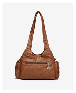 Macro detail of brown soft leather tote bag showing metal flower pendant and zipper pocket