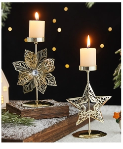 Golden hollow iron candle holder with leaf and star designs on festive snow surface