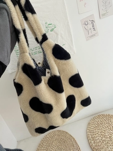 Detail of soft faux fur tote bag with cow print texture and blue checkered lining