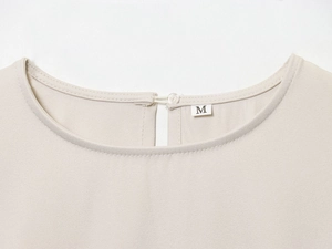 Close-up of beige puff sleeve shirt neckline with button closure and size M tag