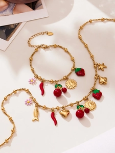 Vue détaillée d'un ensemble de bijoux en acier doré 18k avec breloques aux fruits